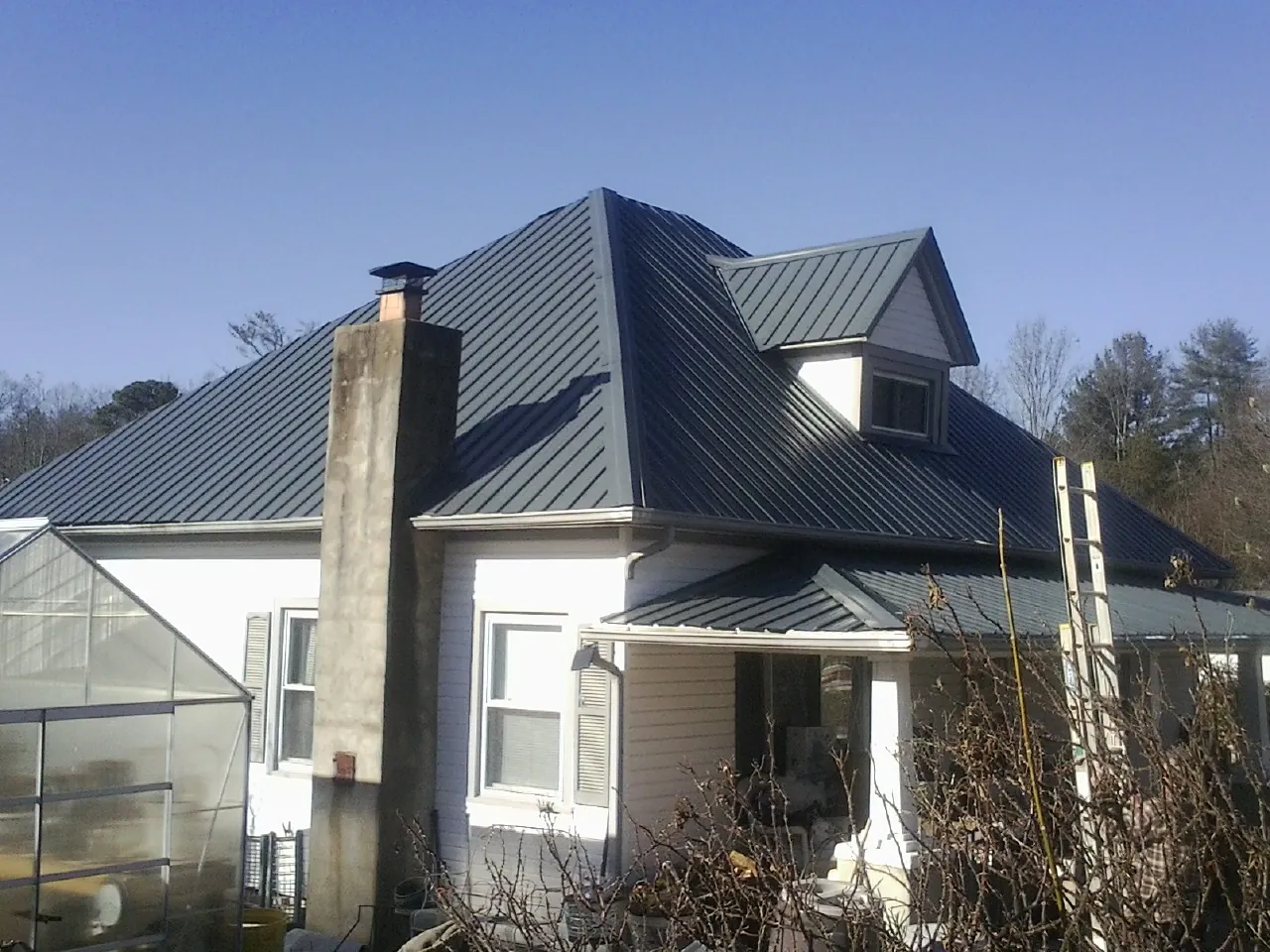 Dark blue standing seam metal roof on a white farmhouse with dormer — Slate & Tile Roof Repair by Roofing Brothers in Dufur