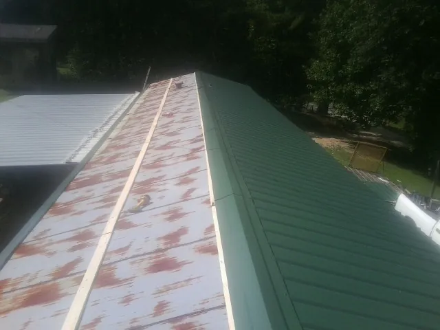 Old rusted panels beside newly installed green metal roofing — Wind Damage Roof Repair by Roofing Brothers in Dufur