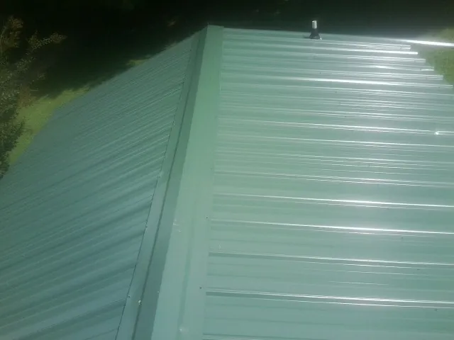New green metal panels meeting at the ridge of a roof — Flat Roof Repair work by our crew in Dufur