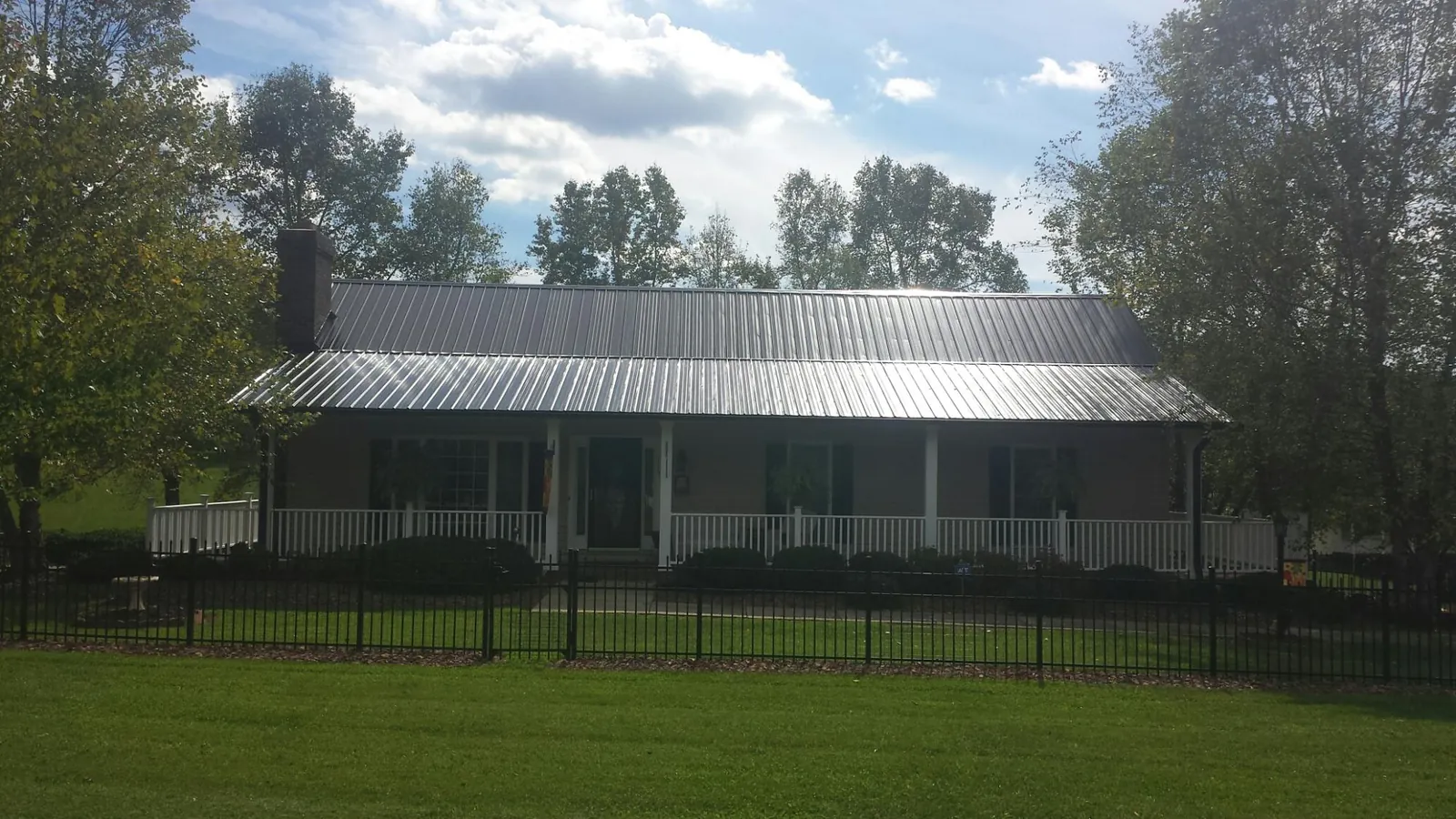 Gray metal roof on a brick ranch with a full width front porch — Gutter Guard Installation work by our crew in Dufur