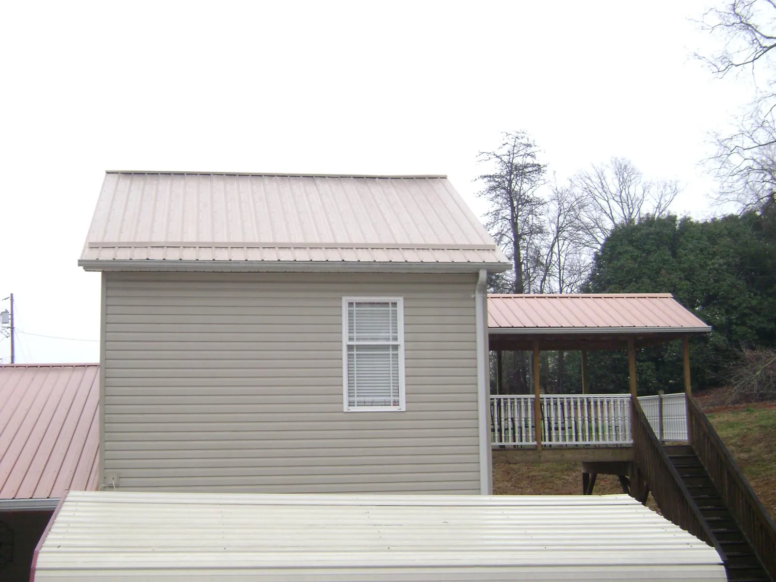 Tan metal roofs on a two story addition and attached porch, from a Roof Replacement job in Dufur