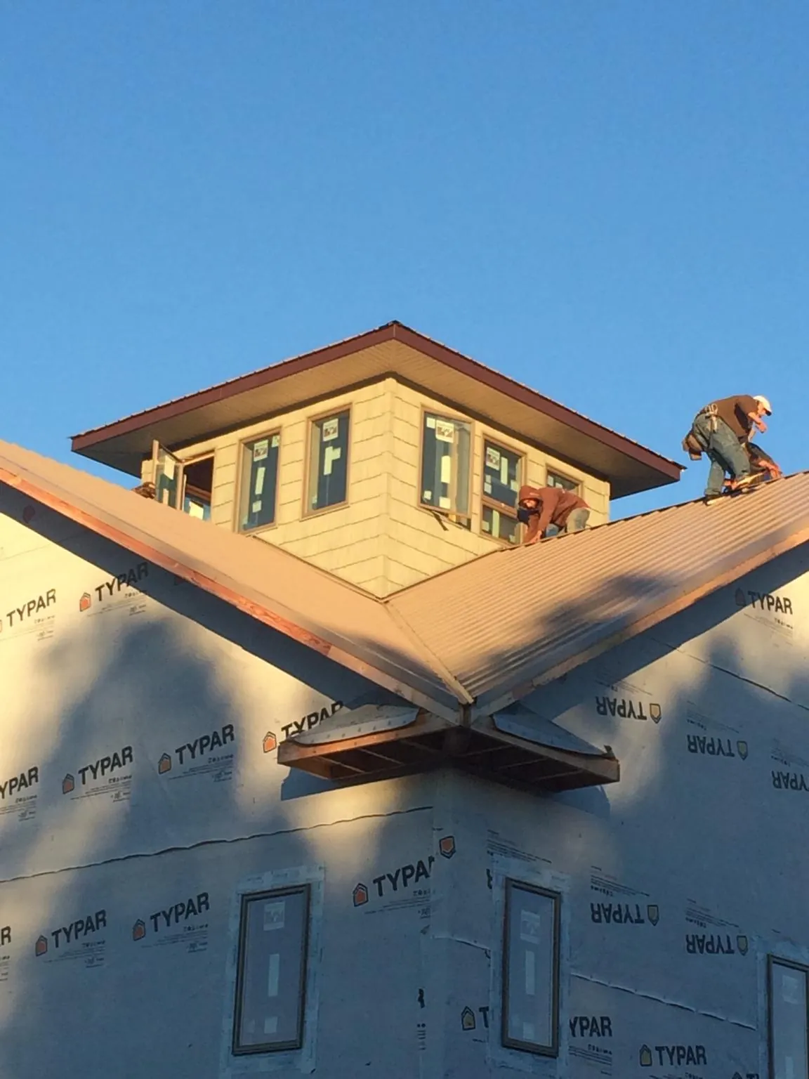 Roofers working around a rooftop cupola on a new metal roof at sunset — Roof Waterproofing in Dufur by Roofing Brothers